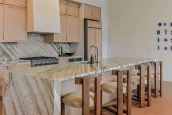 A kitchen with a marble countertop and wooden bar stools.